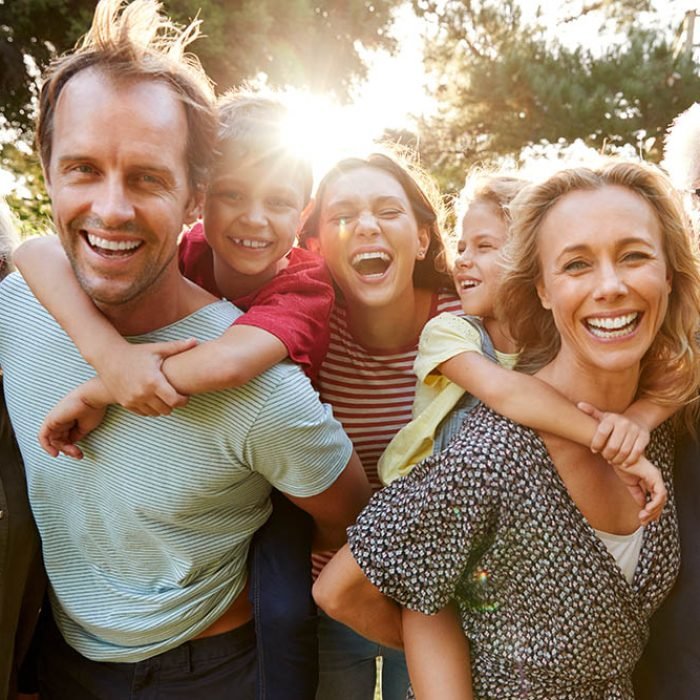 Outdoor Portrait Of Multi-Generation Family Walking In Countryside Against Flaring Sun