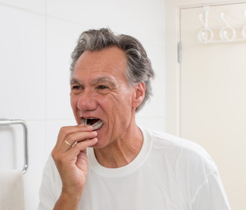 Man Putting in his Night Guard in Front of a Mirror