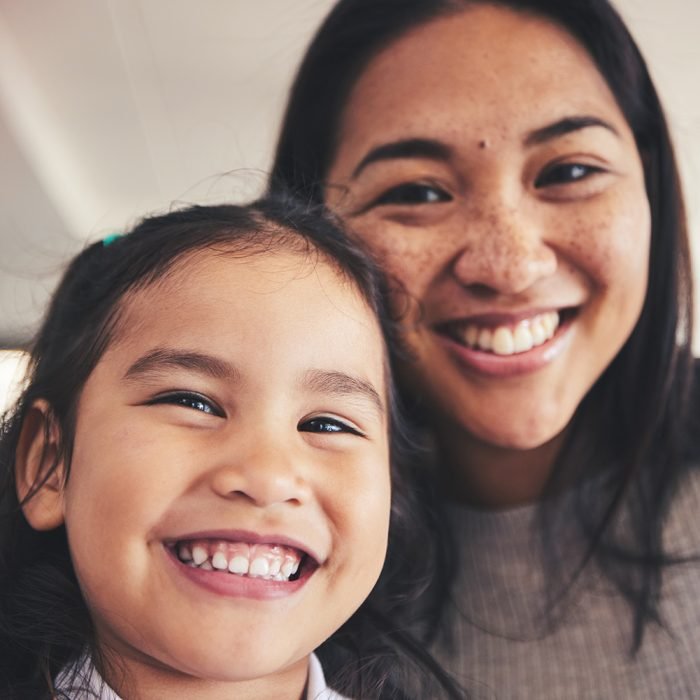 Selfie, smile and portrait of a girl with her mother bonding in the living room of their home. Happy, love and face headshot of Asian child taking a picture with her young mom at their family house