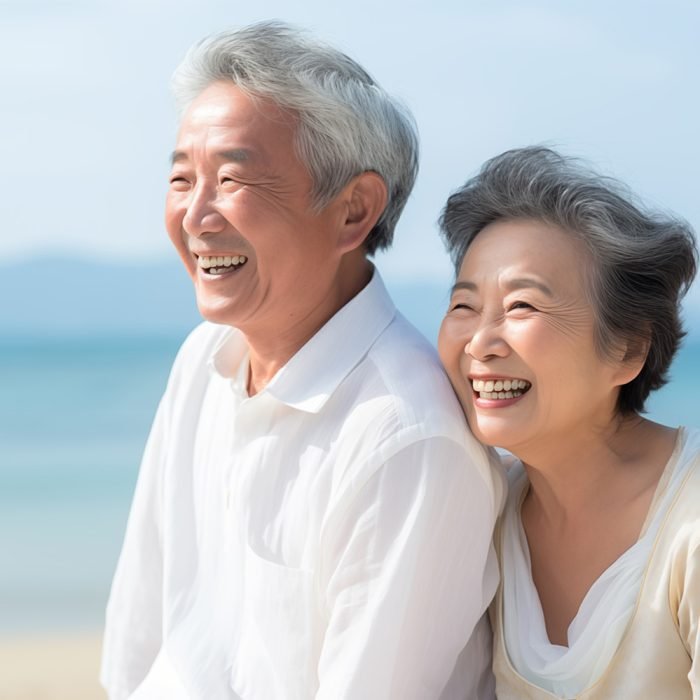 ビーチで微笑むアジア人のシニア夫婦